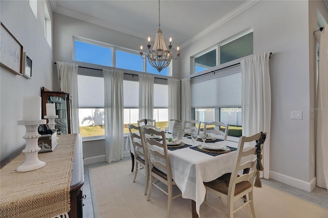 dining space with a chandelier, a high ceiling, crown molding, and baseboards