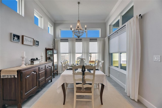 dining space featuring a chandelier, baseboards, a towering ceiling, and crown molding