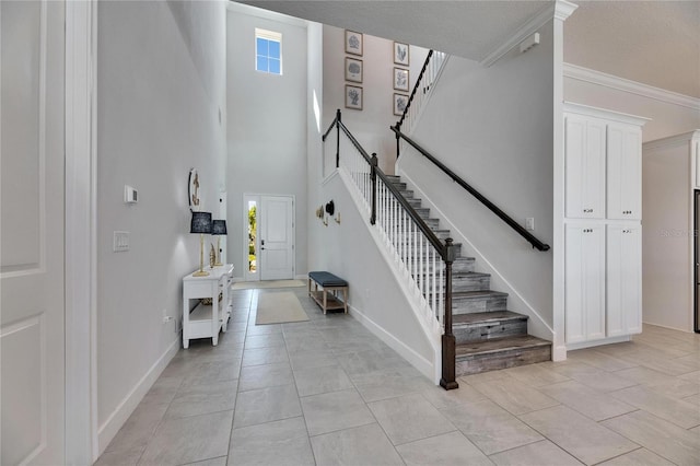 entryway featuring a towering ceiling, light tile patterned floors, baseboards, and stairway