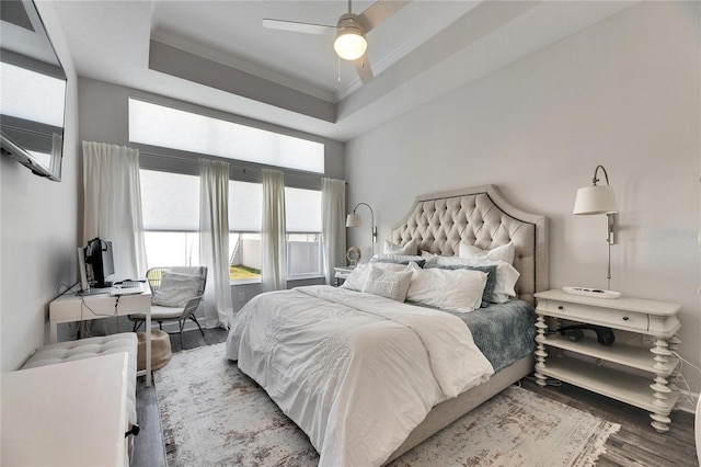 bedroom featuring crown molding, a tray ceiling, ceiling fan, and wood finished floors