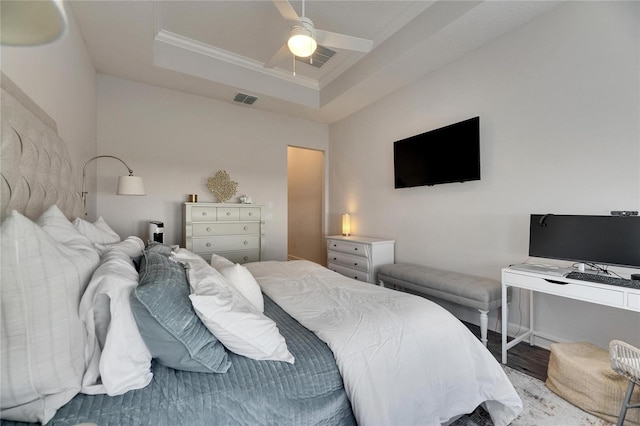 bedroom with visible vents, a raised ceiling, a ceiling fan, ornamental molding, and wood finished floors