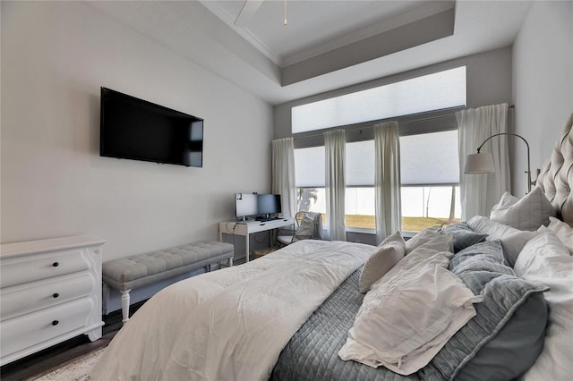 bedroom with ornamental molding, a tray ceiling, and wood finished floors