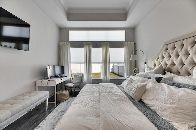 bedroom with ornamental molding, a tray ceiling, and wood finished floors