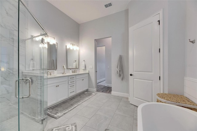 bathroom with double vanity, visible vents, a freestanding bath, a sink, and a shower stall