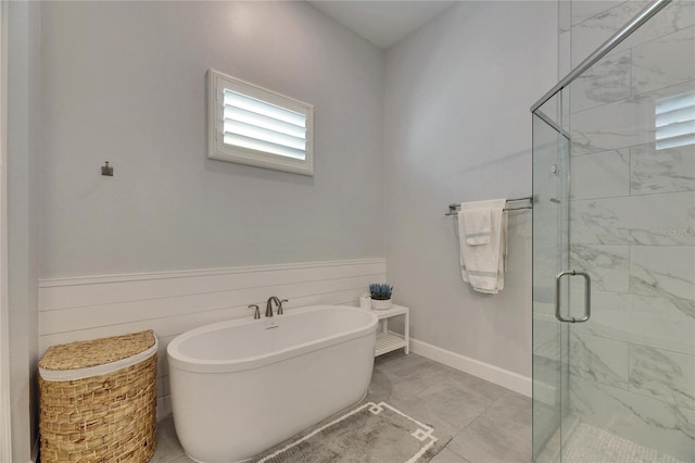 full bathroom with a stall shower, a freestanding tub, wainscoting, and baseboards