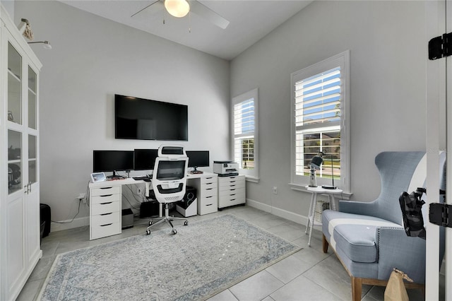 office space with a ceiling fan, baseboards, and tile patterned floors