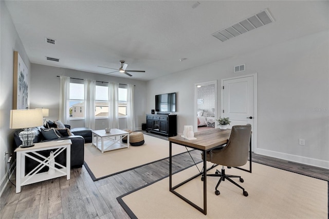 living area with wood finished floors, visible vents, and baseboards