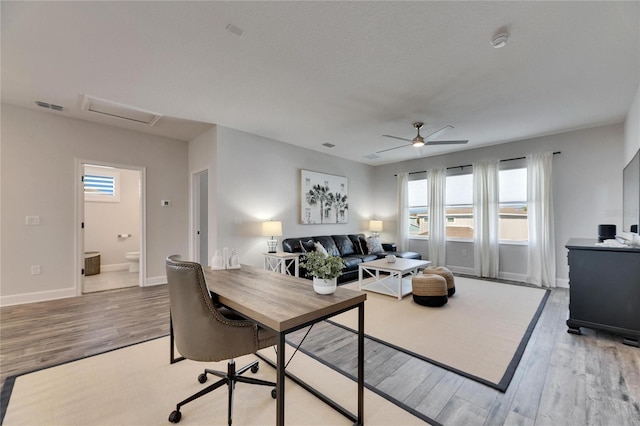 living room featuring baseboards, attic access, visible vents, and wood finished floors