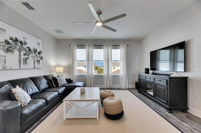 living area with dark wood-style floors, visible vents, ceiling fan, and baseboards