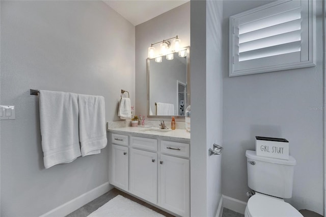 bathroom with toilet, baseboards, and vanity