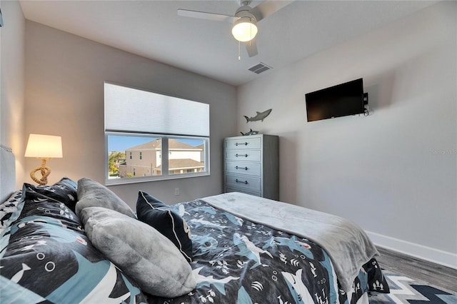 bedroom with a ceiling fan, baseboards, visible vents, and wood finished floors