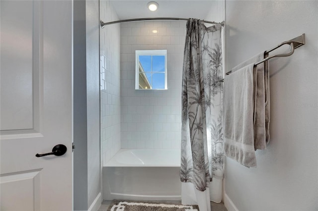 bathroom featuring shower / tub combo and baseboards