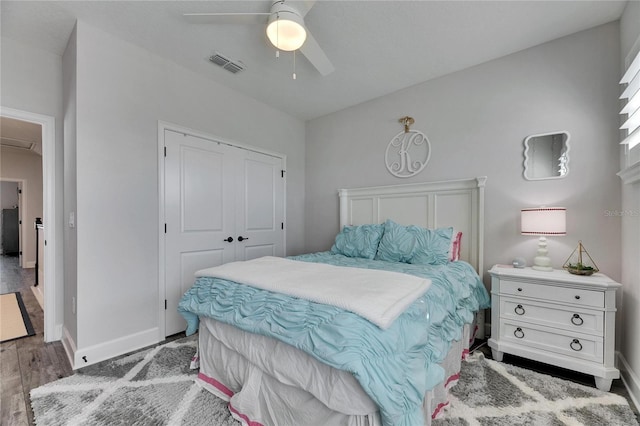 bedroom with a closet, visible vents, baseboards, and wood finished floors