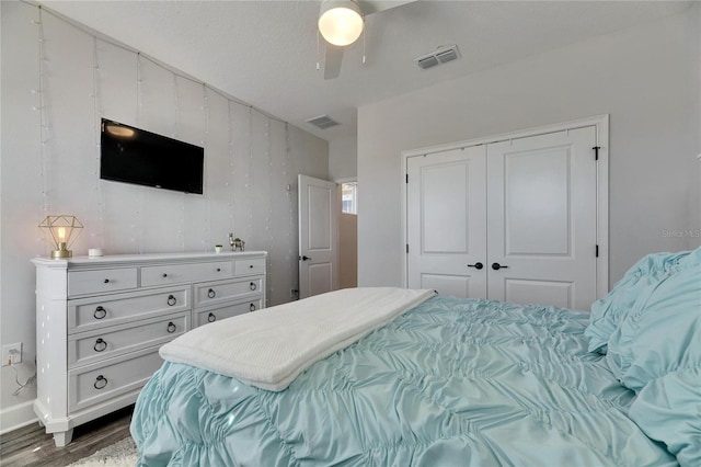 bedroom featuring dark wood-style floors, a ceiling fan, visible vents, and a closet