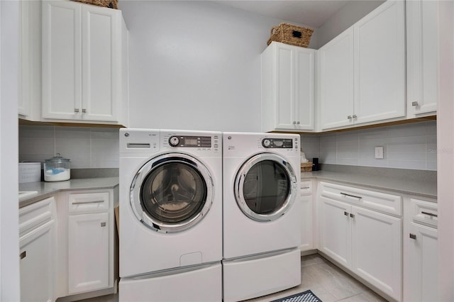 laundry room with washing machine and clothes dryer and cabinet space