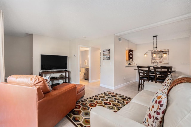 living room featuring baseboards, visible vents, a textured ceiling, and light wood finished floors