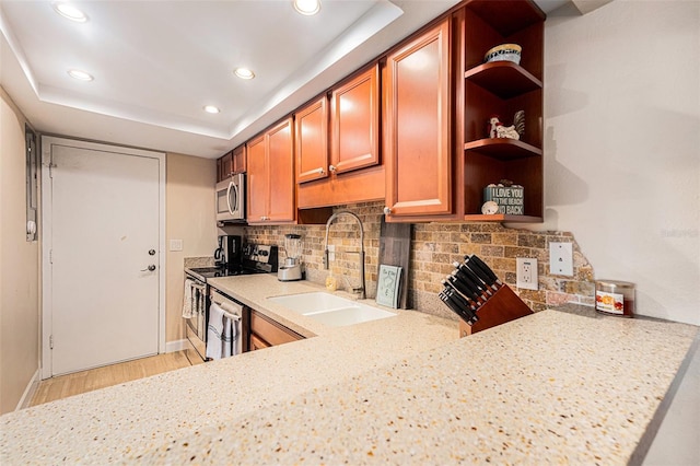 kitchen featuring light wood finished floors, tasteful backsplash, appliances with stainless steel finishes, open shelves, and a sink