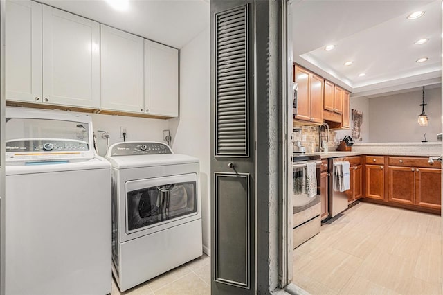 clothes washing area featuring cabinet space, recessed lighting, a sink, and washing machine and clothes dryer