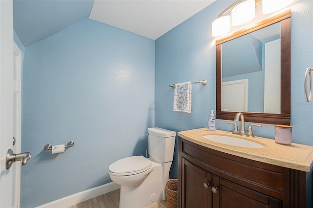 half bath featuring baseboards, toilet, wood finished floors, vaulted ceiling, and vanity