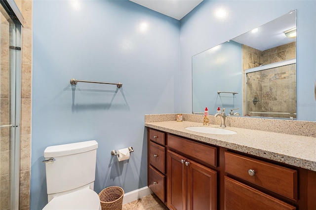 bathroom with baseboards, tiled shower, vanity, and toilet