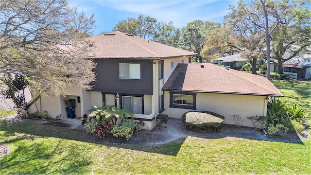 rear view of property with a shingled roof and a lawn