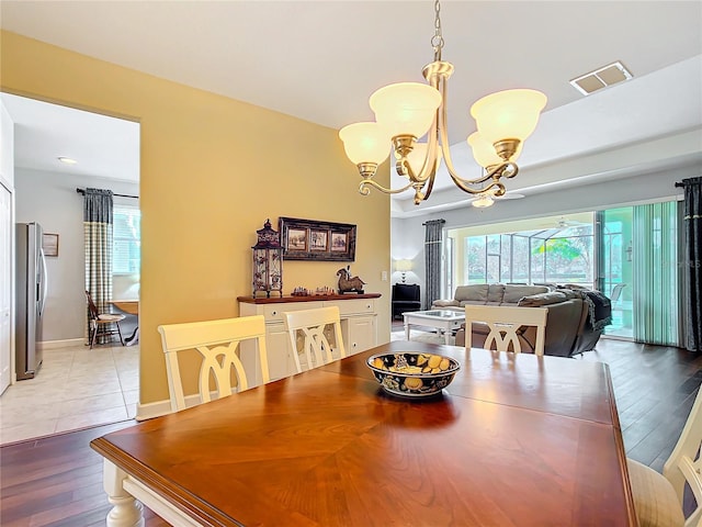 dining room with baseboards, light wood-type flooring, visible vents, and an inviting chandelier