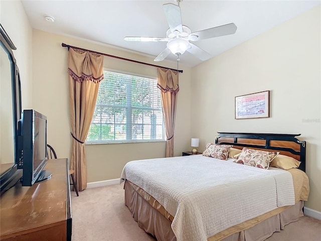 bedroom with light carpet, baseboards, and a ceiling fan