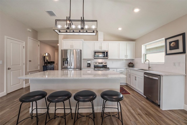 kitchen featuring white cabinets, a center island, hanging light fixtures, stainless steel appliances, and a sink