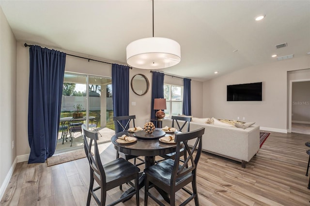 dining space featuring baseboards, visible vents, vaulted ceiling, and wood finished floors