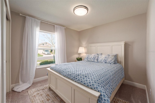 bedroom with light carpet, a textured ceiling, and baseboards