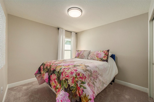 carpeted bedroom featuring a textured ceiling and baseboards