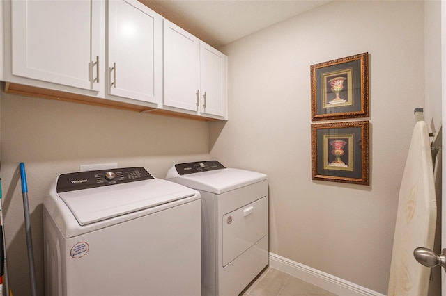 washroom with light tile patterned floors, independent washer and dryer, cabinet space, and baseboards