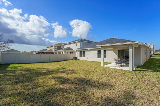 back of house with stucco siding, a fenced backyard, a lawn, and a patio