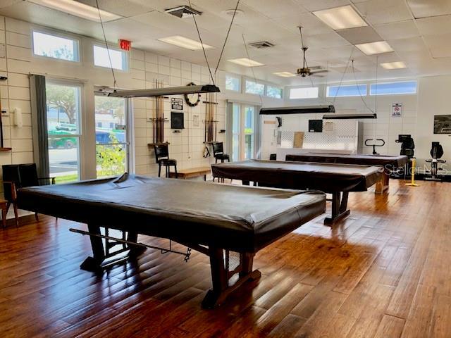 recreation room with ceiling fan, billiards, a towering ceiling, and wood finished floors