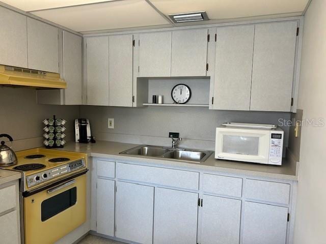 kitchen with white microwave, under cabinet range hood, range with electric cooktop, a sink, and open shelves