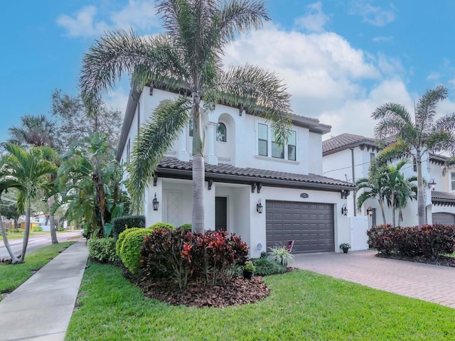 view of front of home featuring a garage, a tiled roof, decorative driveway, stucco siding, and a front yard