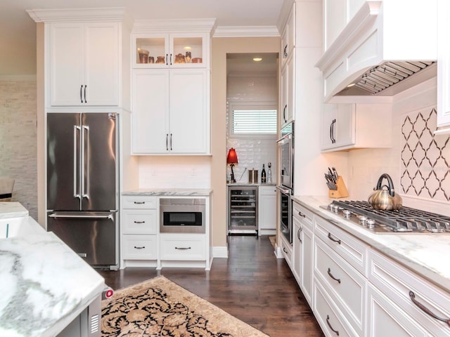 kitchen featuring beverage cooler, glass insert cabinets, appliances with stainless steel finishes, custom exhaust hood, and white cabinetry