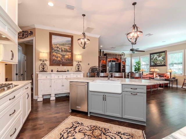 kitchen with crown molding, pendant lighting, a center island with sink, and a sink