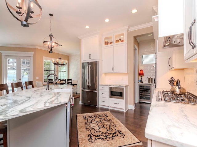 kitchen with a chandelier, glass insert cabinets, appliances with stainless steel finishes, light stone counters, and white cabinetry