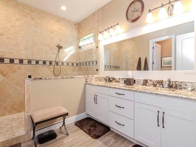 bathroom featuring double vanity, a walk in shower, a sink, and wood finished floors