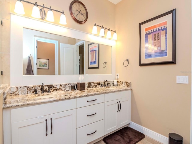 bathroom featuring double vanity, wood finished floors, a sink, and baseboards