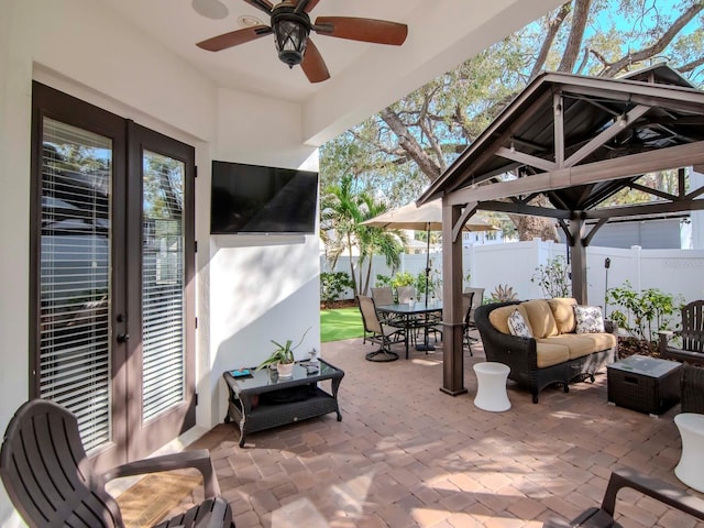 view of patio / terrace featuring a fenced backyard, an outdoor living space, a ceiling fan, a gazebo, and outdoor dining space