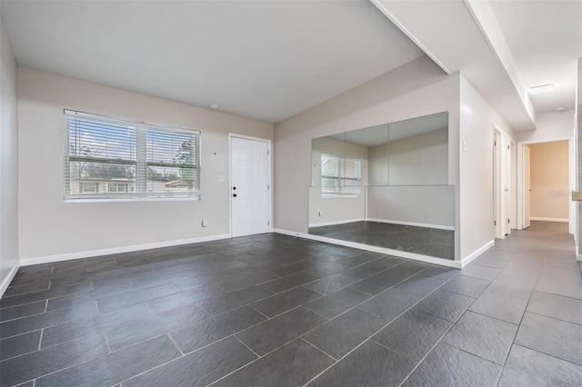 unfurnished room featuring dark tile patterned floors and baseboards