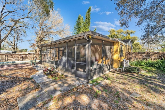 rear view of property featuring fence and a sunroom