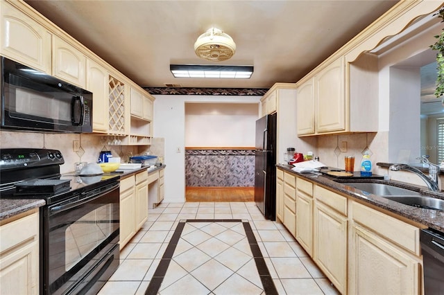 kitchen featuring light tile patterned floors, black appliances, dark stone counters, and a sink