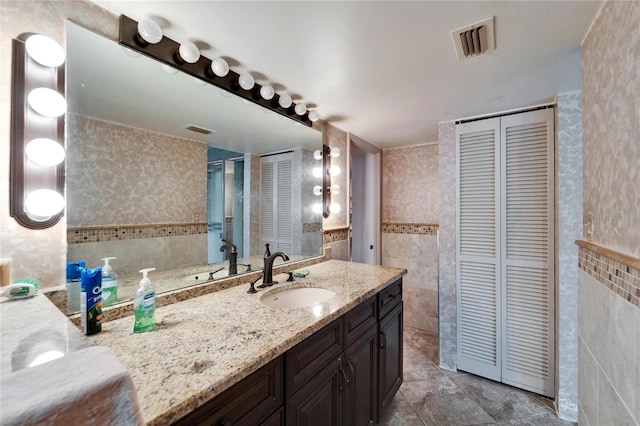 bathroom with visible vents, a closet, and tile walls