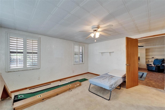 carpeted bedroom with ceiling fan, multiple windows, baseboards, and a textured wall