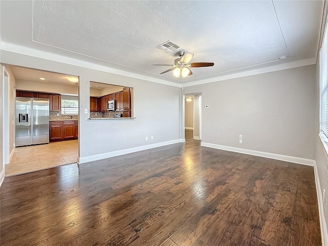 unfurnished living room featuring light wood-type flooring, baseboards, visible vents, and a textured ceiling