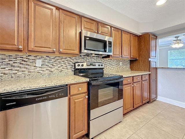 kitchen featuring appliances with stainless steel finishes, brown cabinets, light tile patterned flooring, and tasteful backsplash