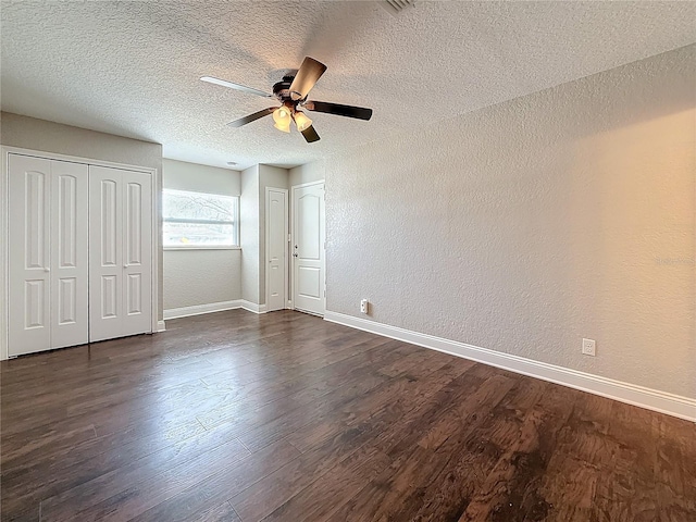 unfurnished bedroom with dark wood finished floors, two closets, and baseboards